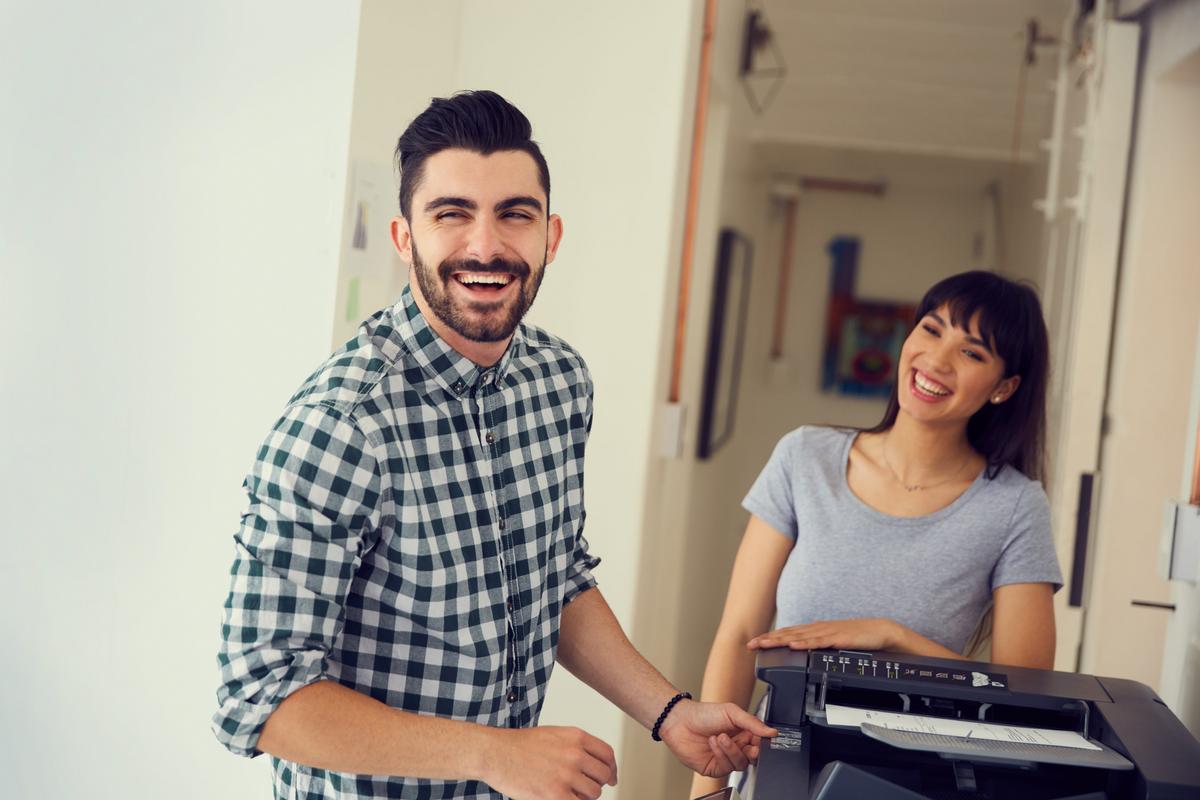 Smiling businessman and coworker using an office copier