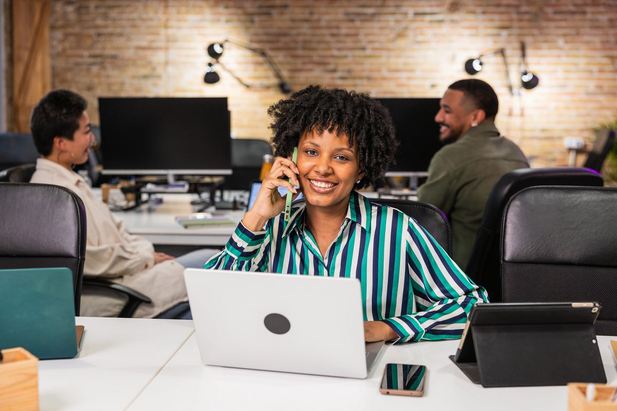 Employee taking a call at her desk in an open office
