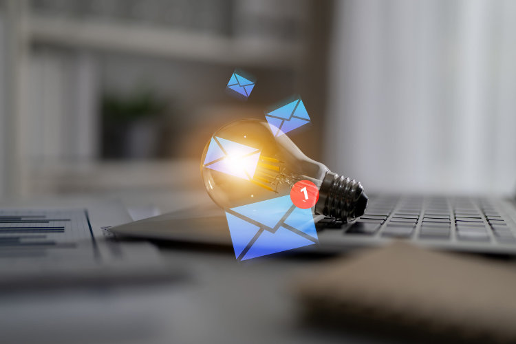 Light bulb alongside email notifications on laptop symbolizing bright ideas